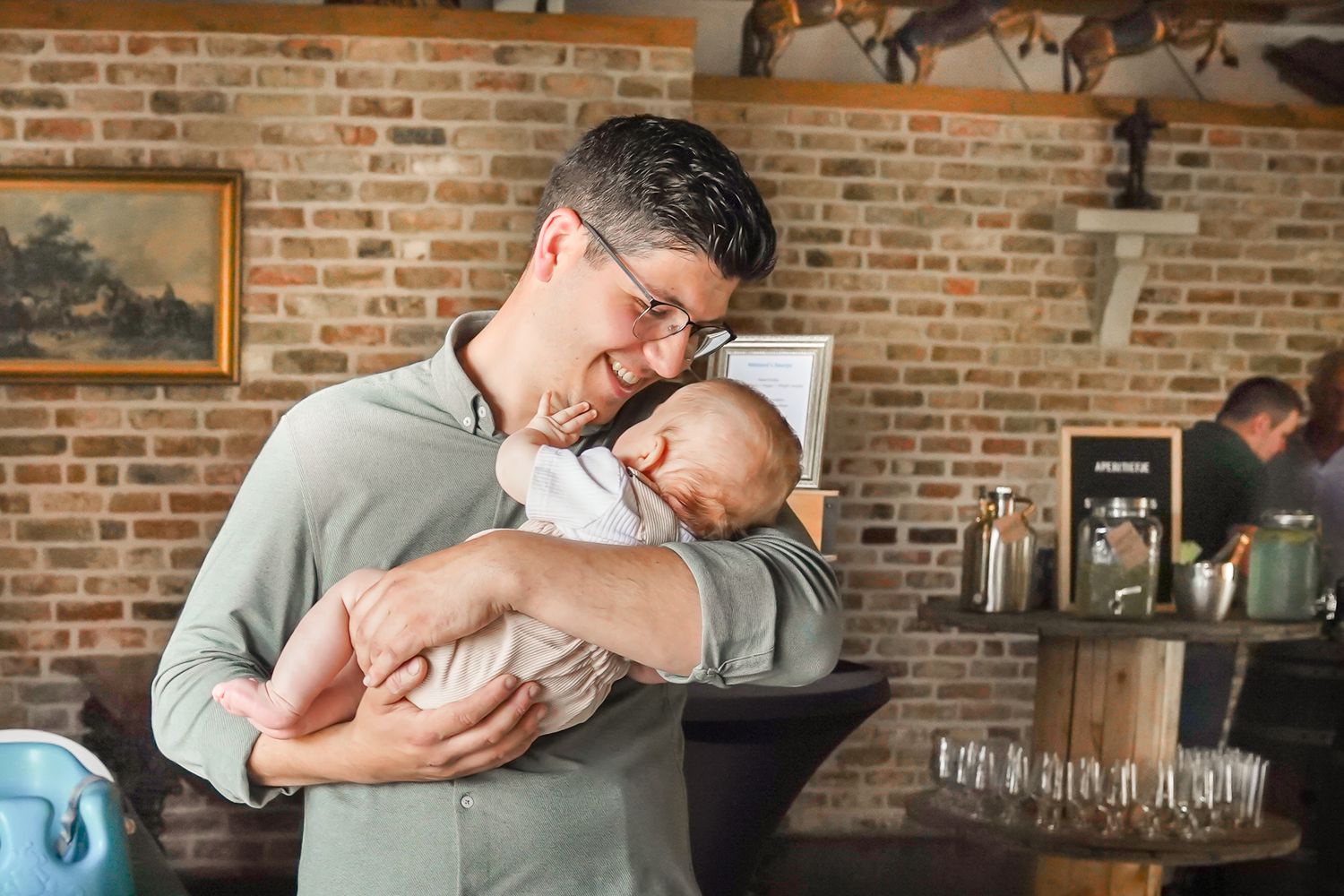 A tender moment showing a parent cradling a sleeping infant against a rustic brick wall background.