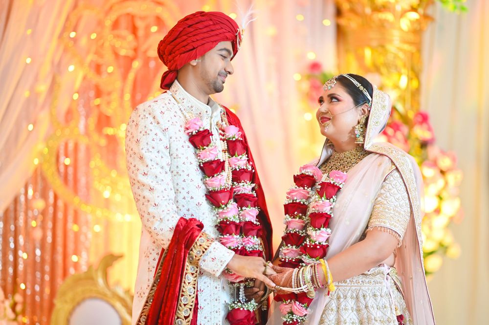 Traditional Indian wedding ceremony with couple wearing red and white garments exchanging vows.