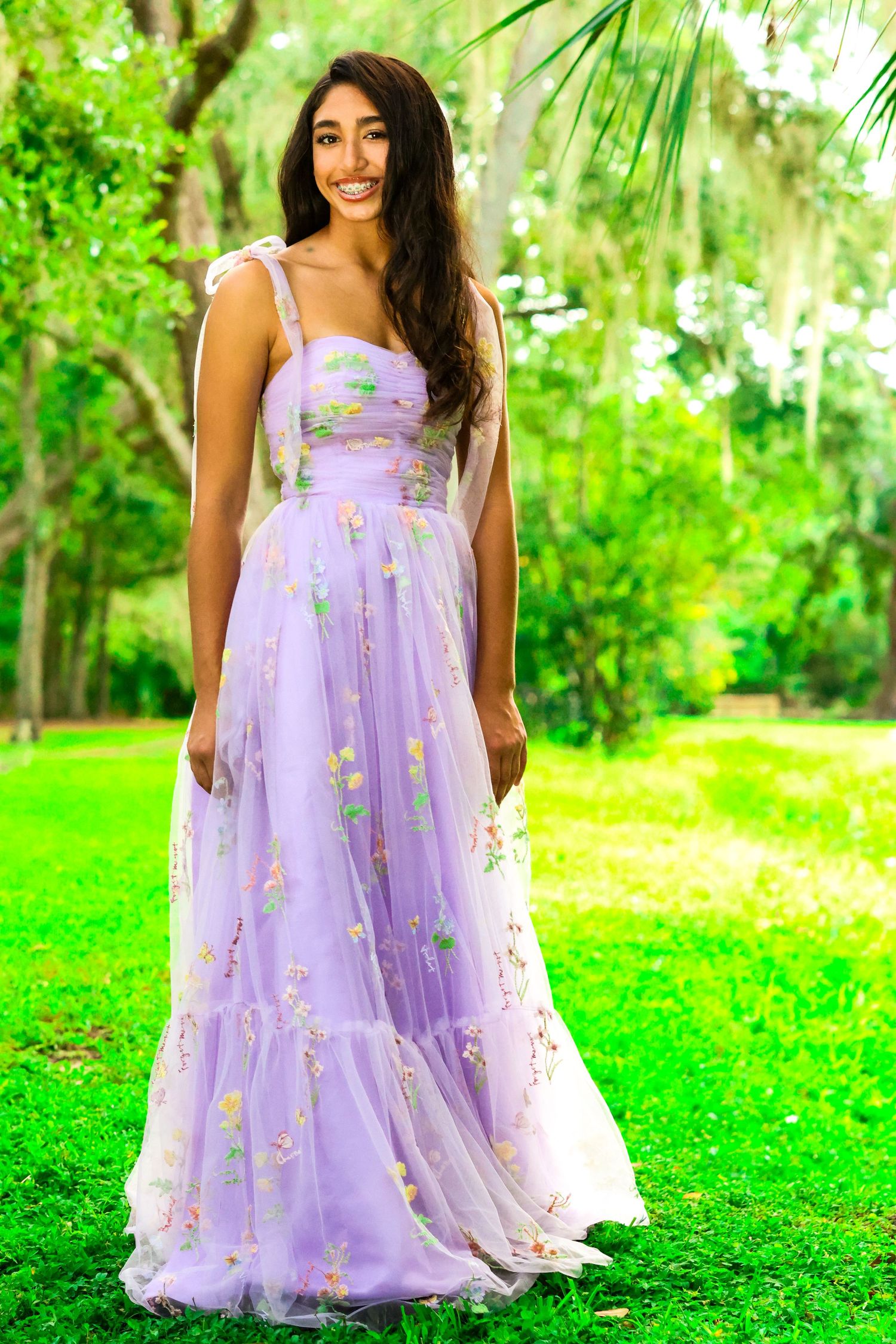 Lavender tulle dress with delicate floral details photographed in a lush garden setting.