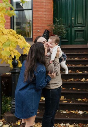 A couple shares a romantic moment on brick steps surrounded by yellow autumn leaves on a fall day.