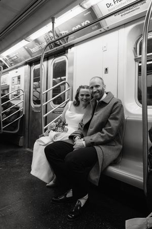 A Brooklyn couple sits together on a subway train bench in black and white photography.