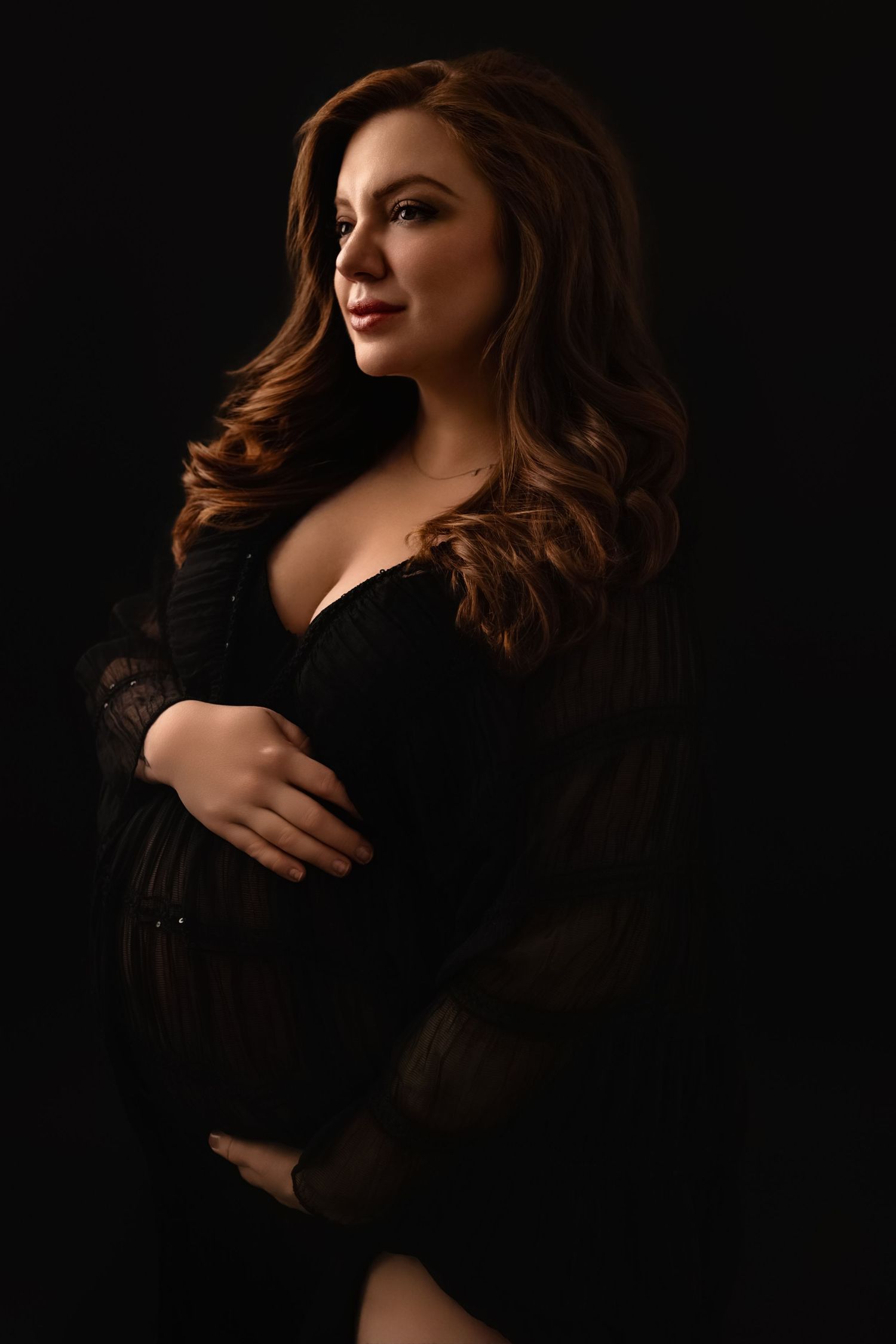 Beautiful pregnant mama holds her pump against a black backdrop, captured by Charlottesville maternity and newborn photographer.