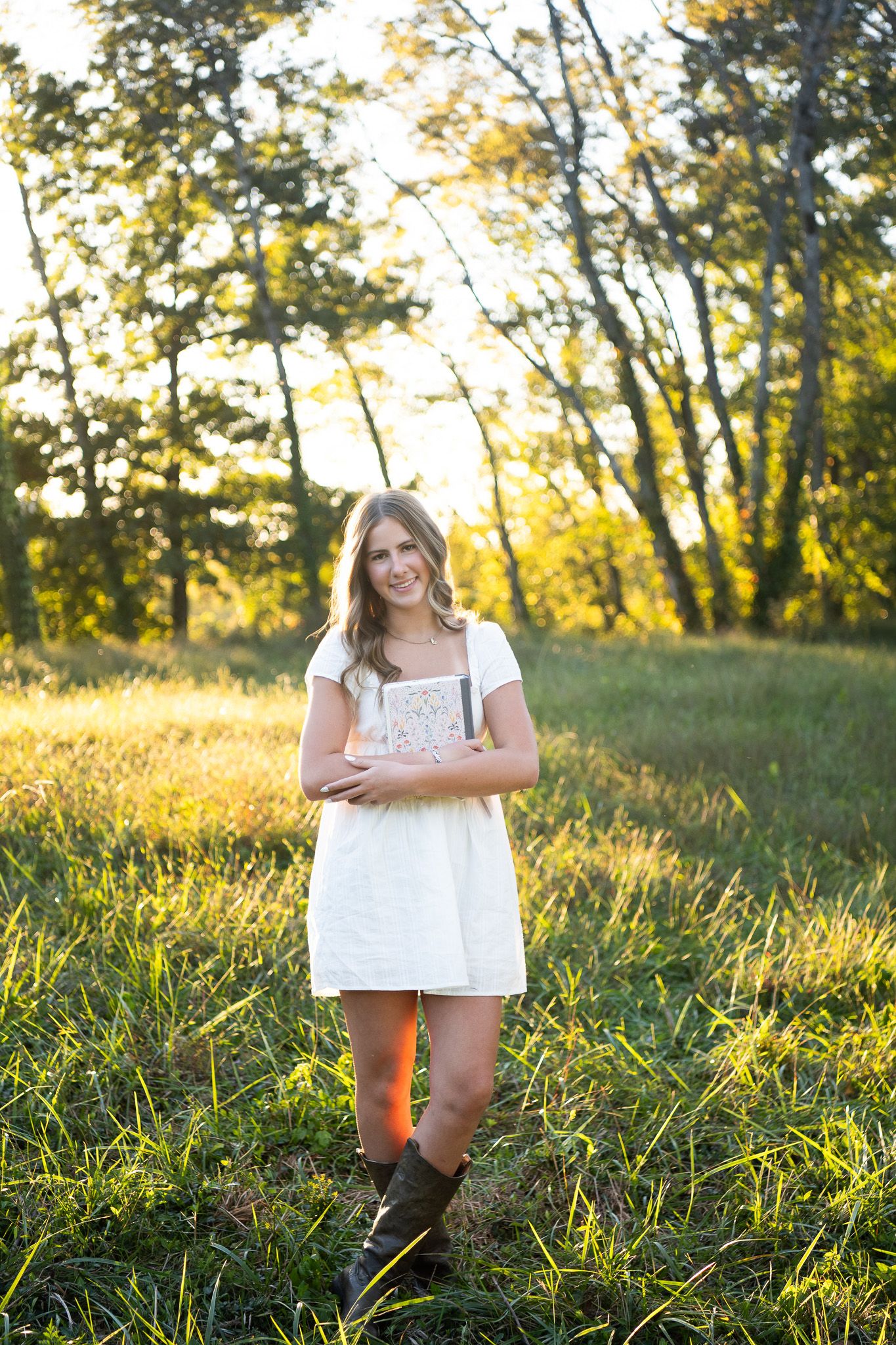 Outdoor portrait series in golden sunlit meadow with tall grass and trees during sunset.