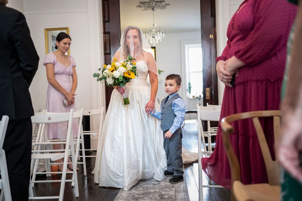 Wedding party members in burgundy and white dresses gather during an elegant indoor ceremony.
