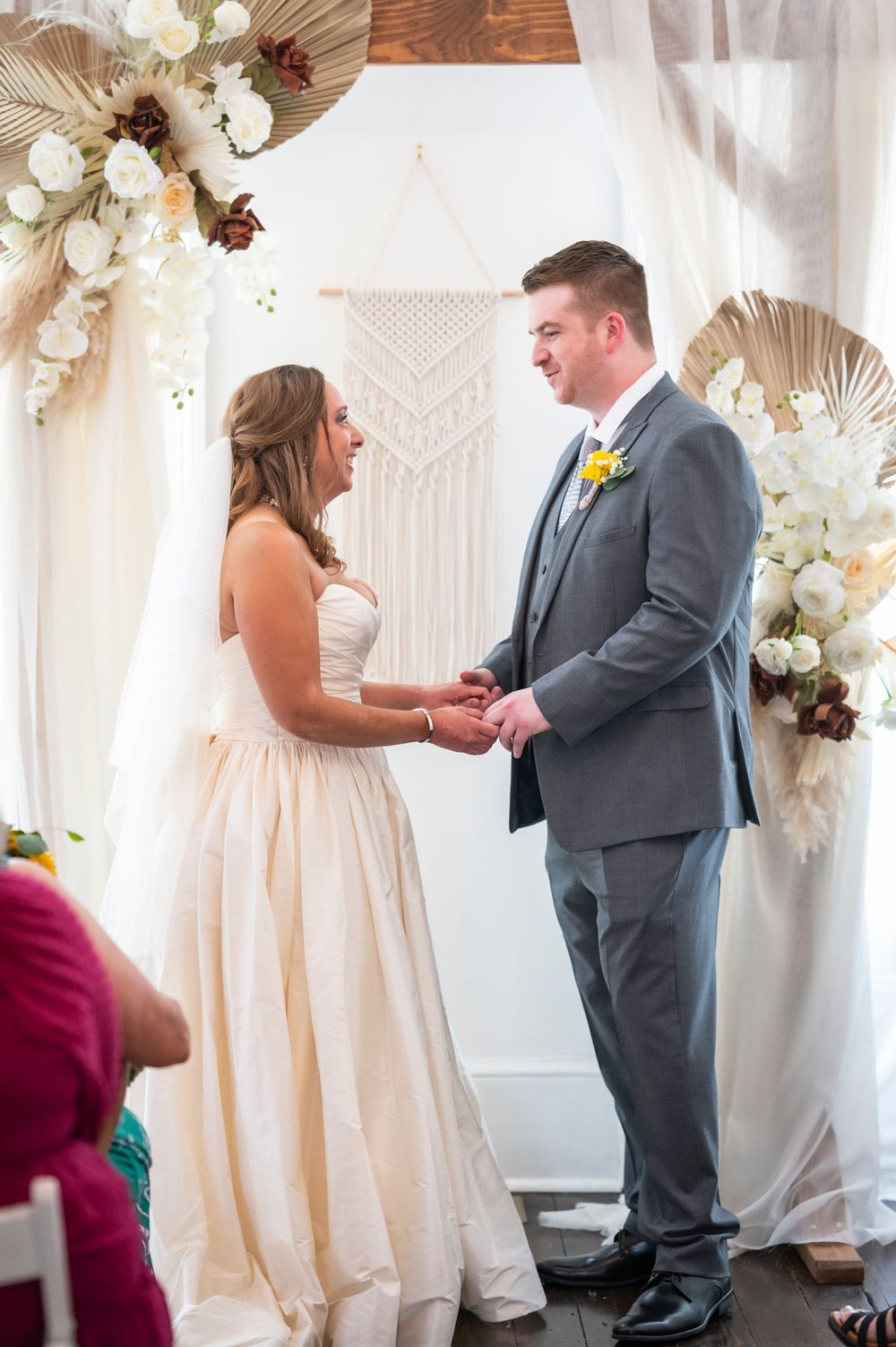 A couple shares an intimate first look moment at their wedding ceremony under elegant white floral decorations.