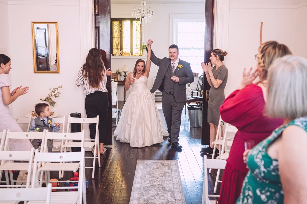 Wedding guests browse elegant bridal gowns displayed on mannequins in a bright boutique showroom.