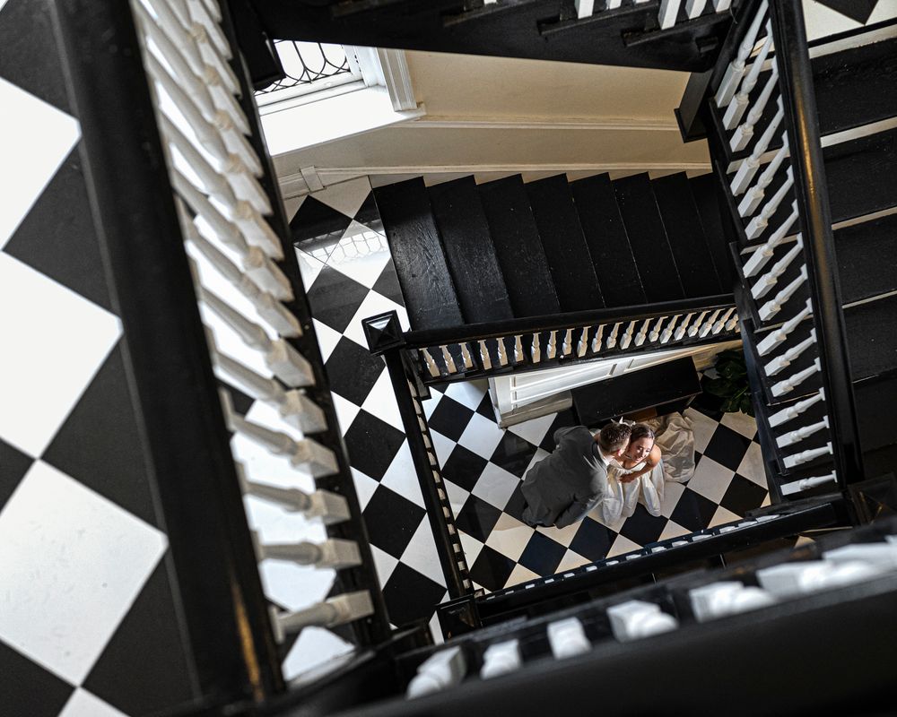 Looking up a spiral staircase with black and white geometric pattern on walls creating dramatic visual effect.