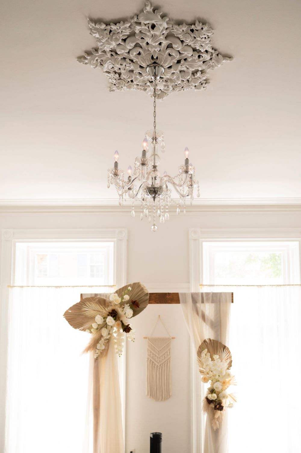 Elegant white room interior with ornate crystal chandeliers and white curtains creating a luxurious, bright atmosphere.