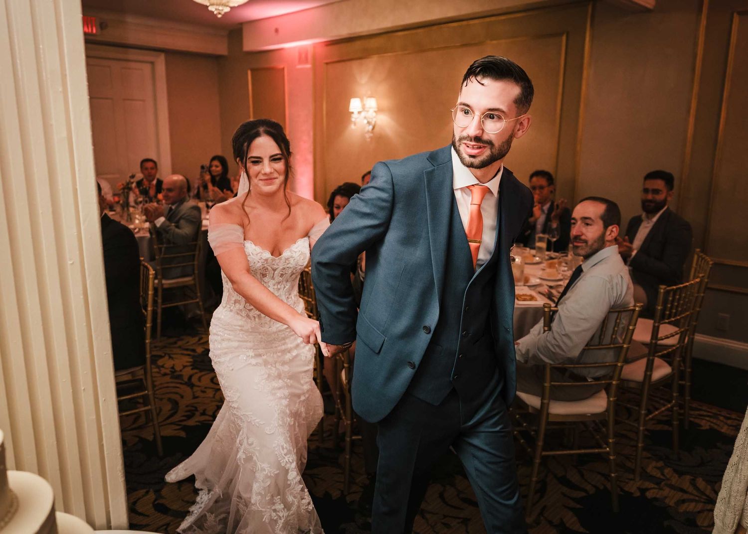 The bride and groom holding hands walk into the Dome room at their wedding reception in the Lenox Hotel