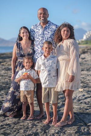 Family portrait session on Oahu's coastline at sunset featuring coordinated blue and white outfits.