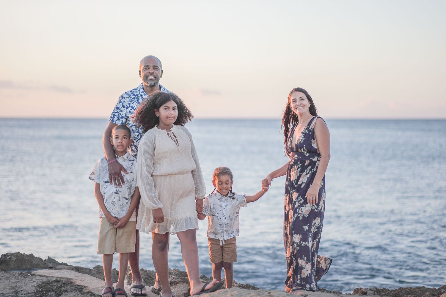 Family gathered on a North Shore Oahu beach during a sunset family photography session in coordinated coastal-inspired outfits.