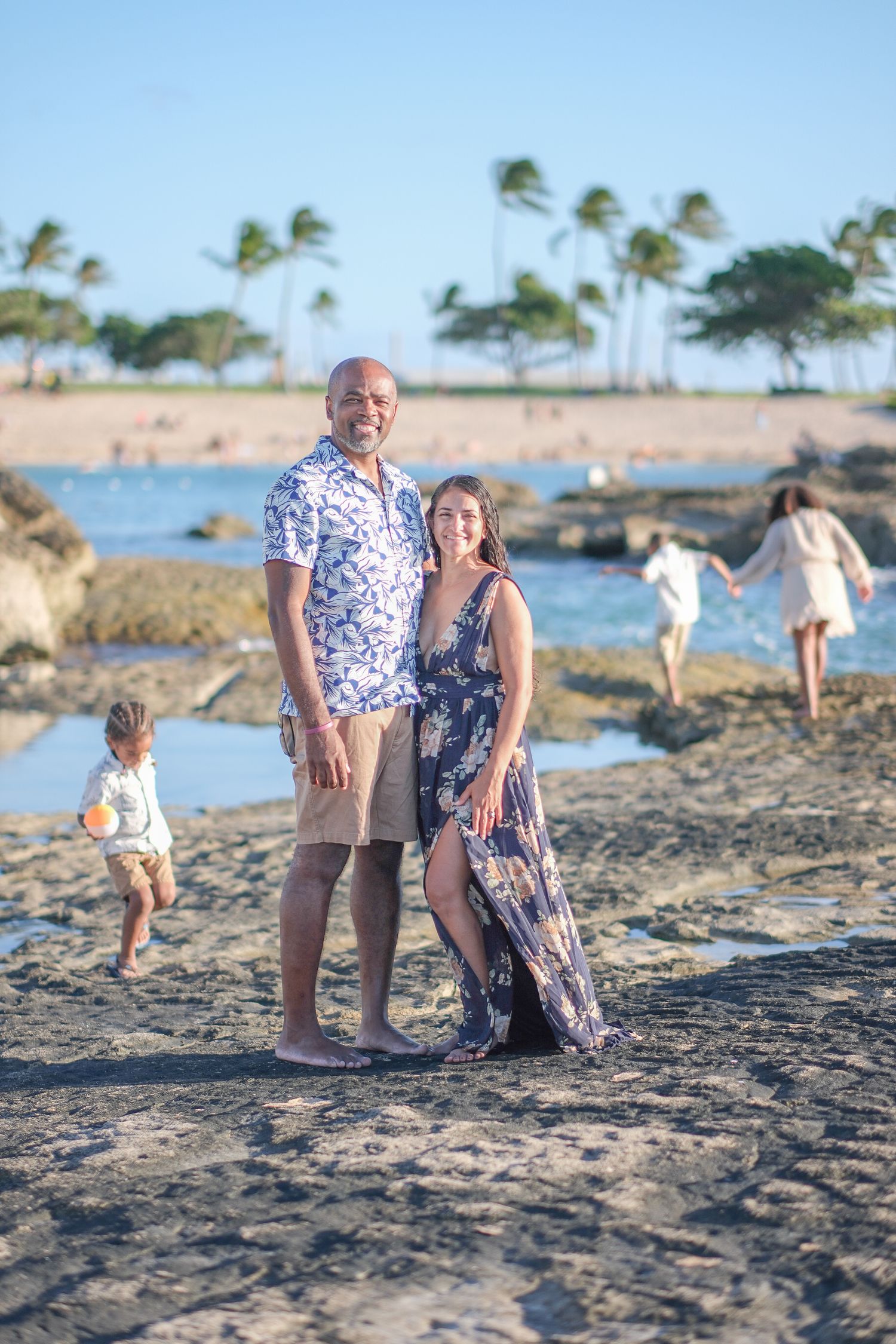 Family enjoying a North Shore Oahu beach photography session with palm trees and ocean views in the background.