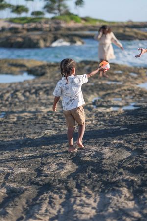 Child exploring the shoreline during a North Shore Oahu family photography session at sunset.