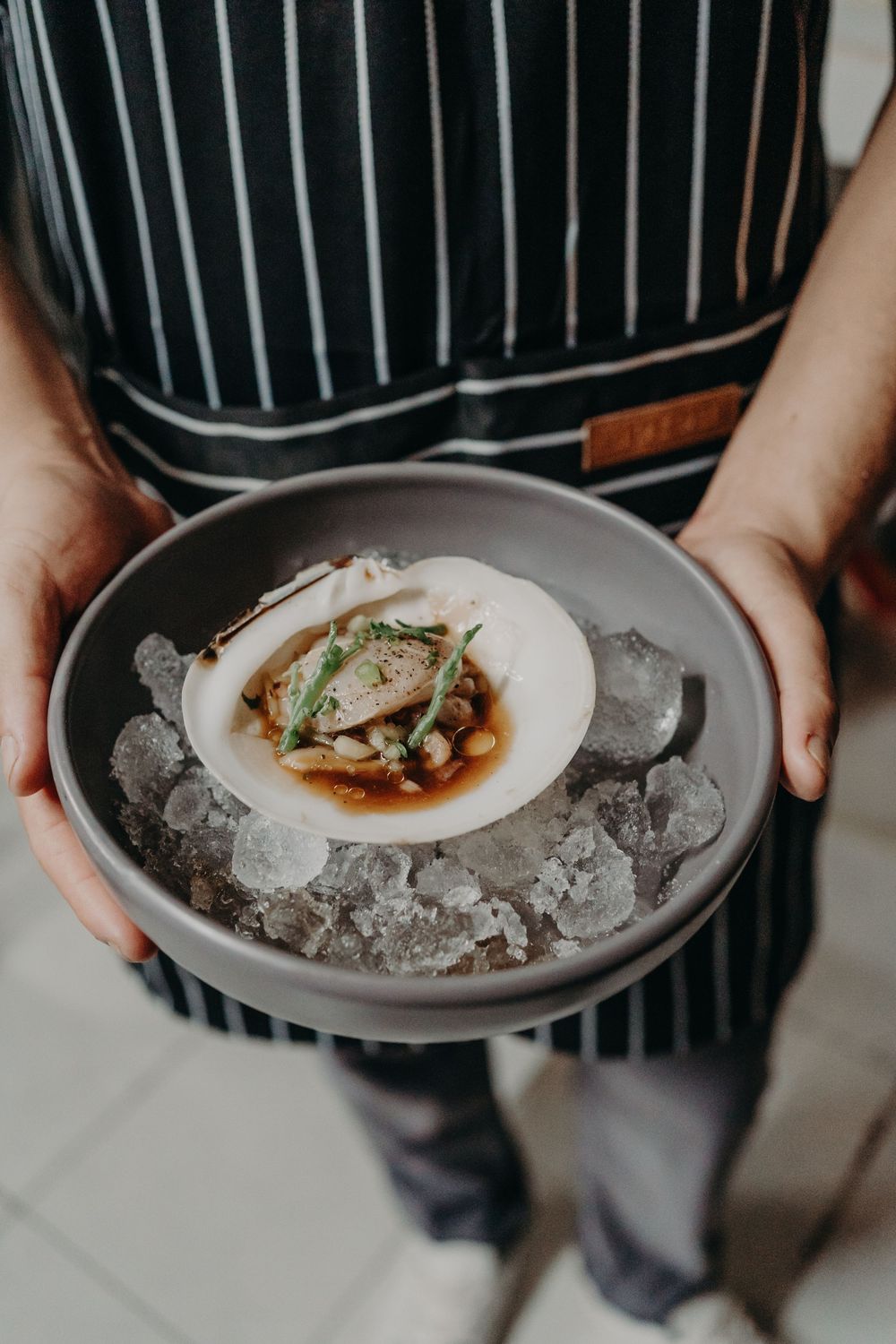 A series of plated dishes being served on beds of crushed ice in elegant restaurant style presentation.