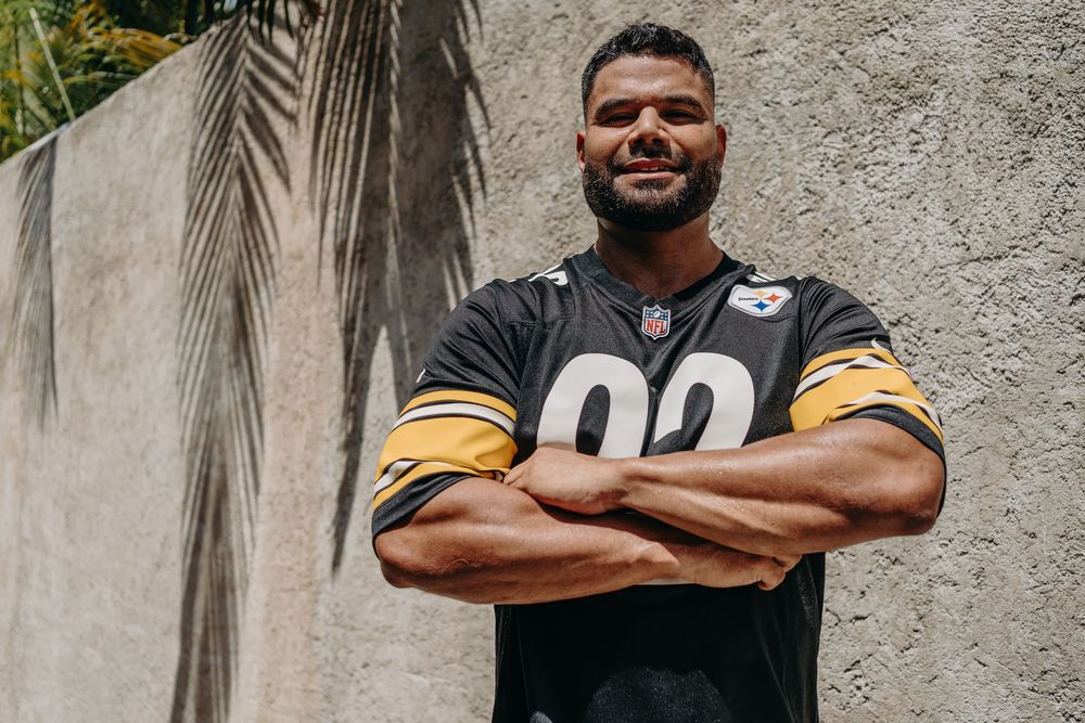 NFL player wearing a black and yellow Pittsburgh Steelers jersey number 92 poses with arms crossed against concrete wall.