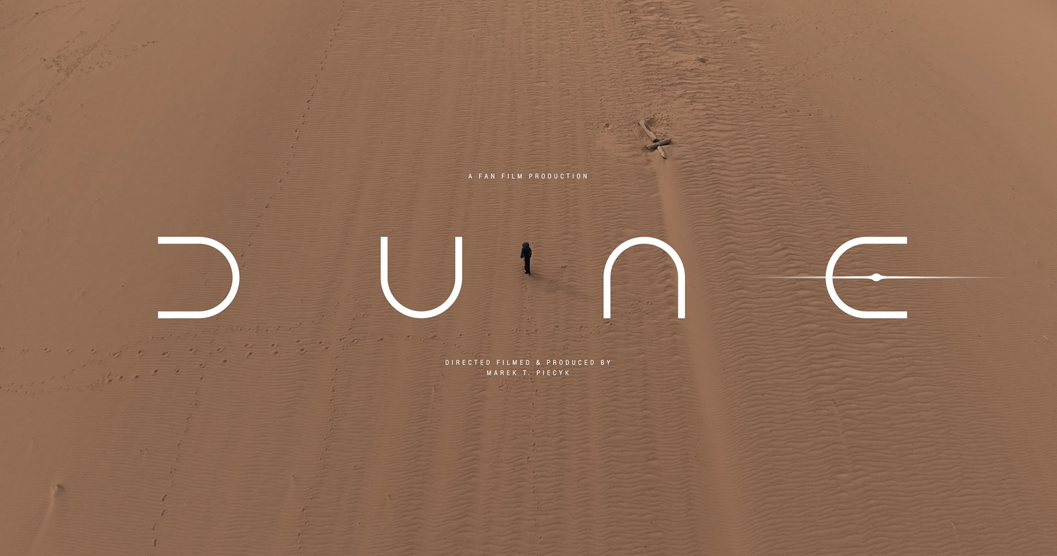 A cinematic still from the movie Dune showing a figure wearing a hooded desert wrap against a dark background.