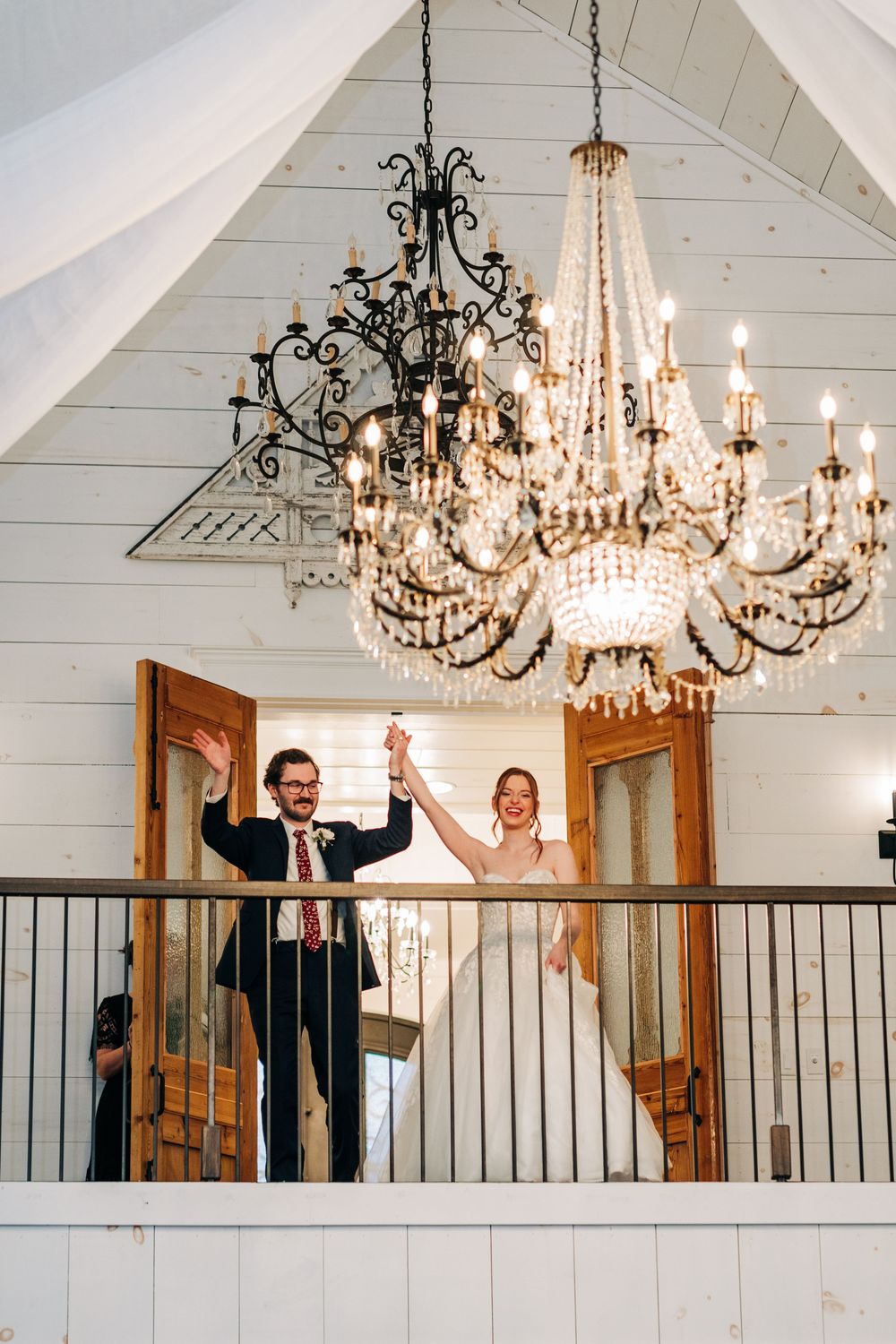 A sequence of celebratory moments captured under elegant crystal chandeliers in a rustic white-paneled venue.