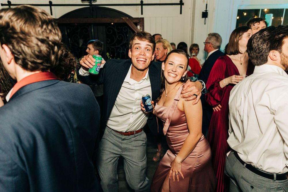 Wedding party dances and celebrates on crowded dance floor during evening reception.