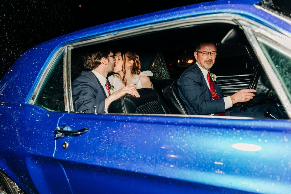 Wedding couple shares intimate moment in blue car decorated for their special day.