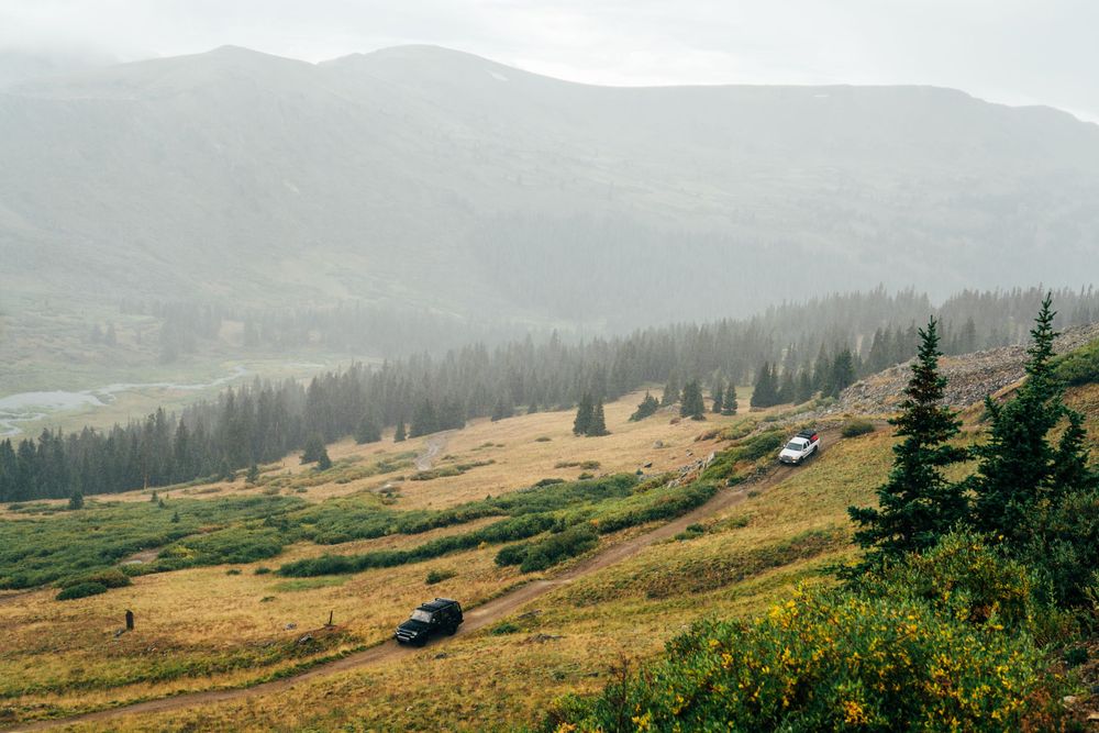 Panoramic mountain landscape with evergreen forests and rolling hills under cloudy skies.