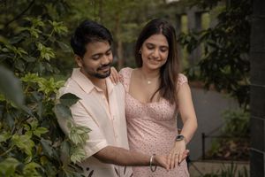 South Asian couple sharing a romantic moment standing close together among lush green garden foliage.