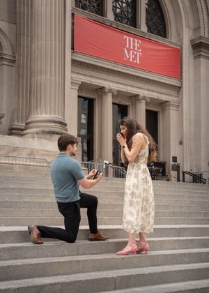 Man proposing on one knee on the steps of The Met museum in New York City.