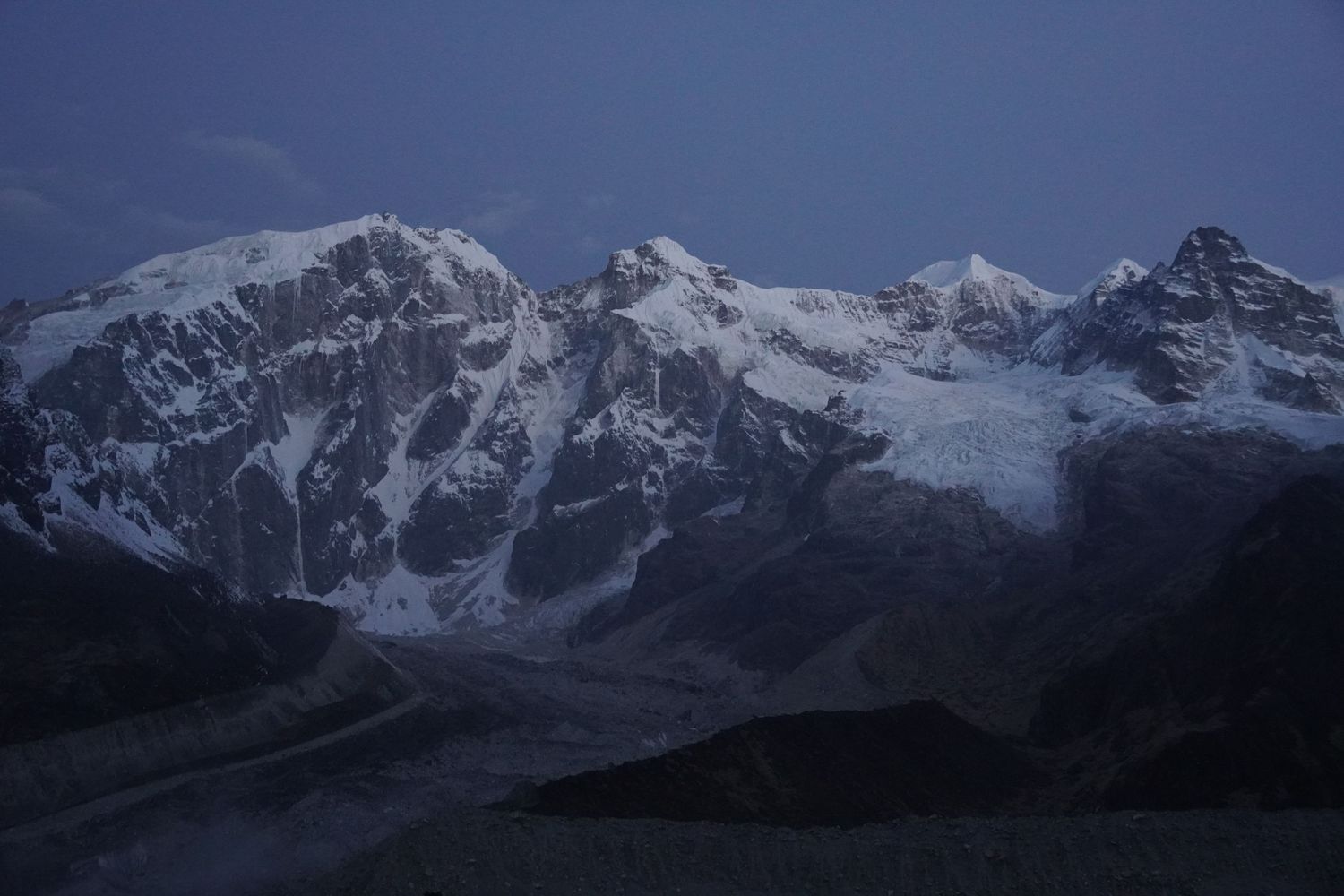 Majestic snow-covered mountain peaks under a dark, moody sky, fine art landscape photography from the high trails.