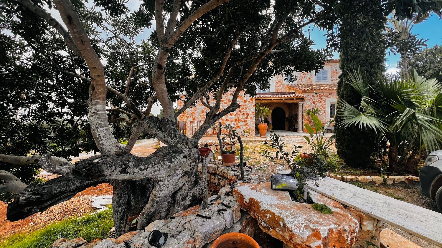 A rustic stone building surrounded by lush trees and greenery in a tranquil outdoor setting.