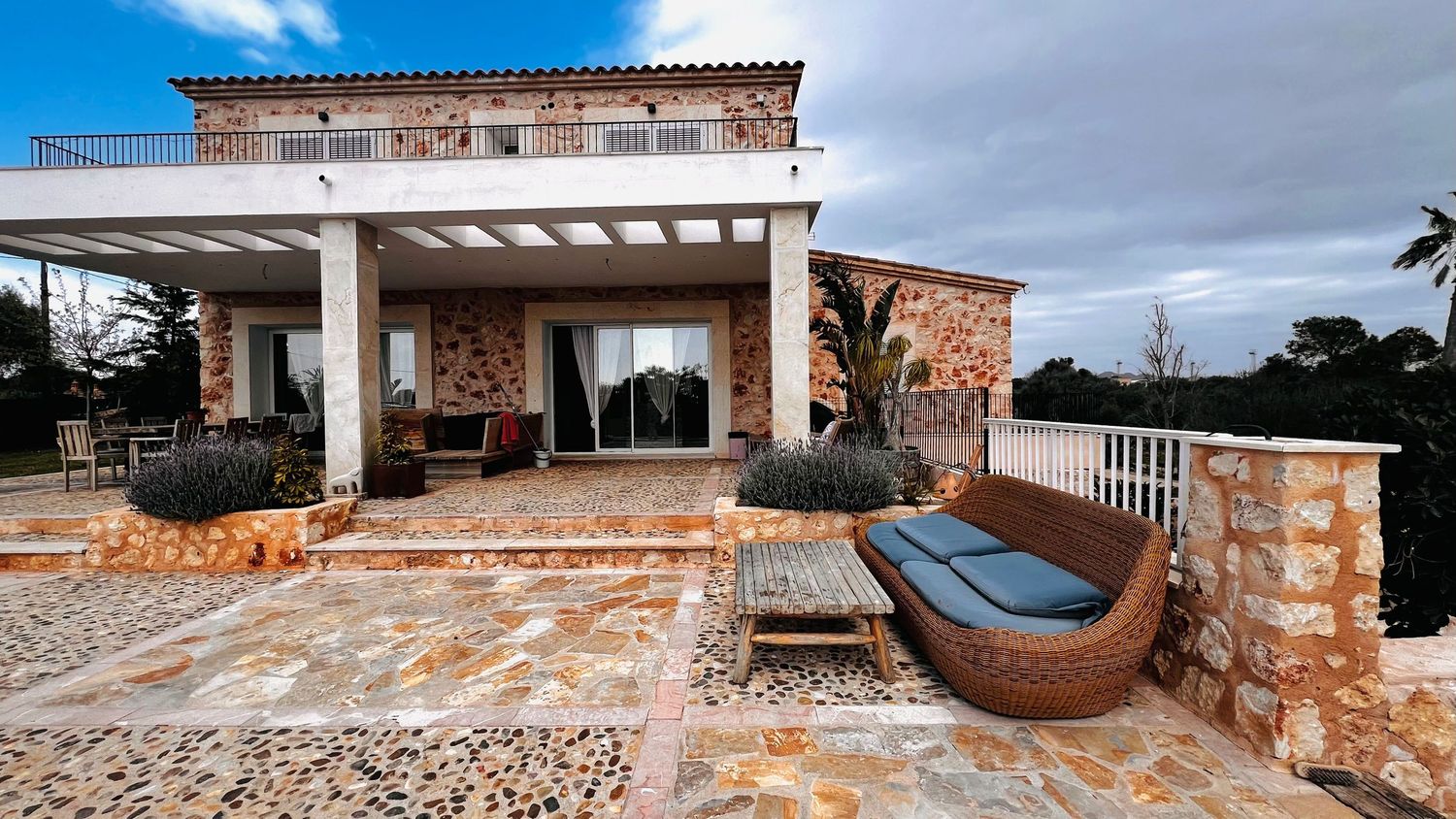 A large, luxurious Mediterranean-style villa with a spacious outdoor patio and seating area.