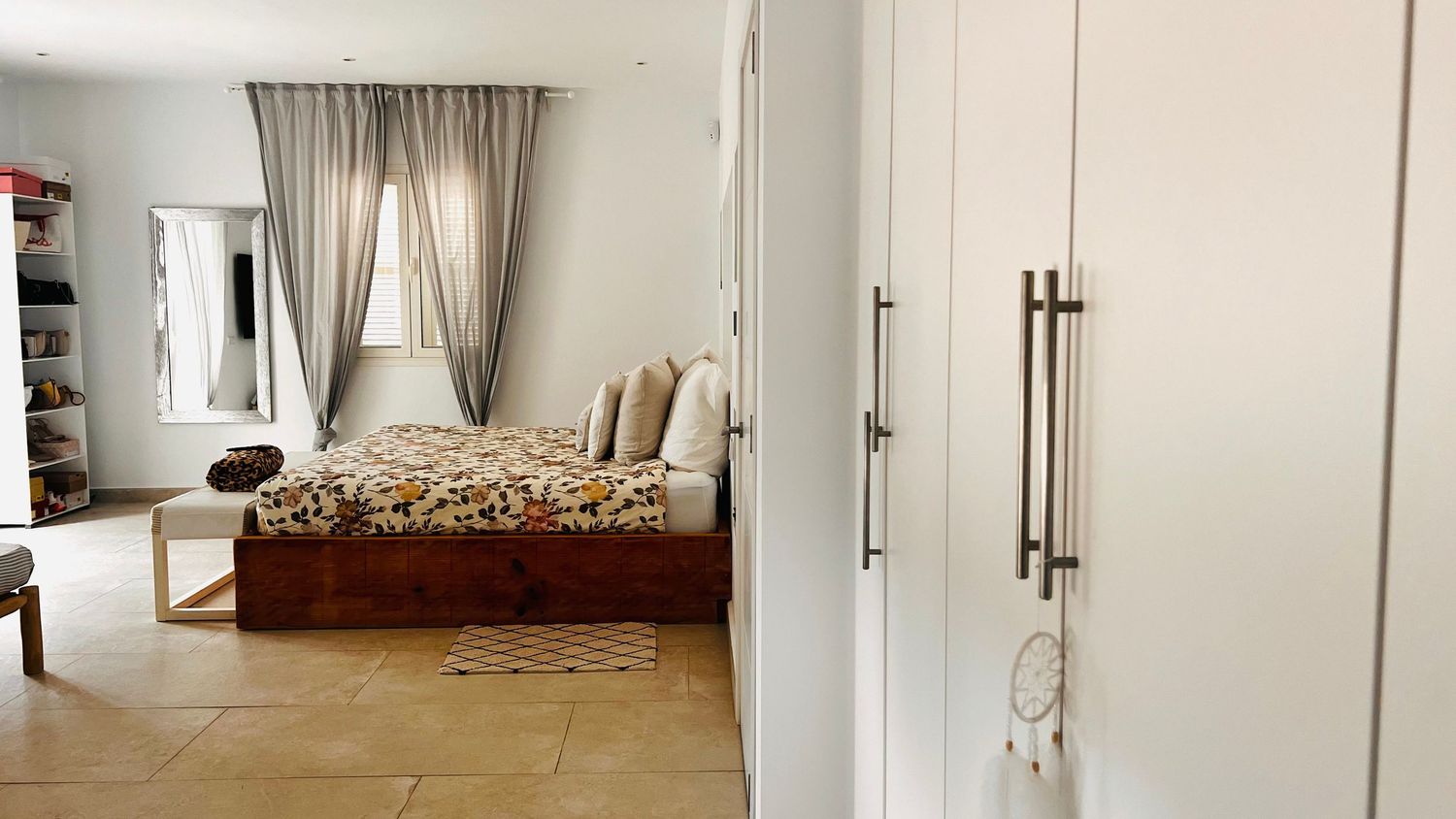 A cozy bedroom interior with a large bed, curtains, and a wardrobe visible.