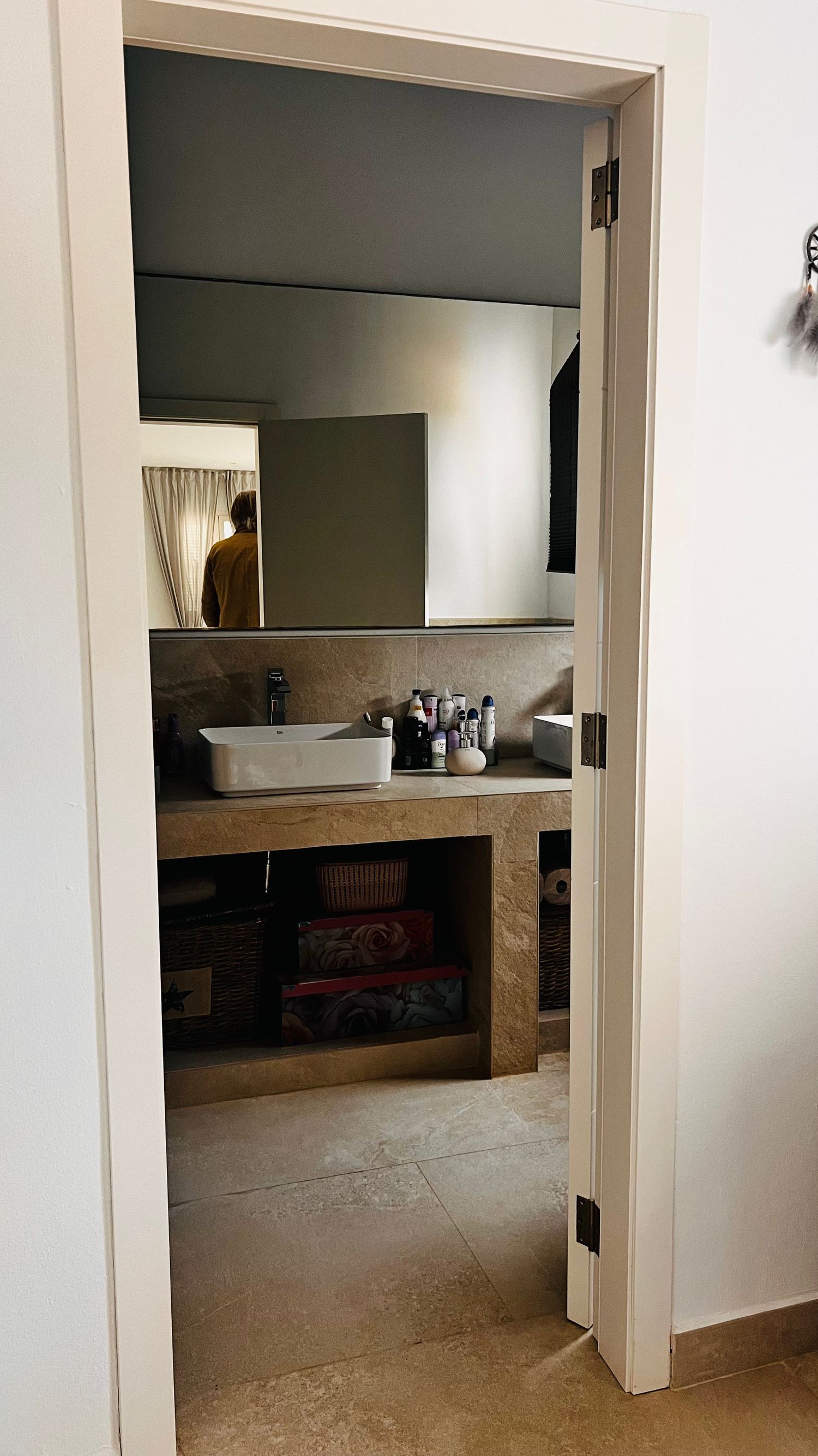 The image shows a bathroom vanity with a mirror, shelves, and various personal care items on display.
