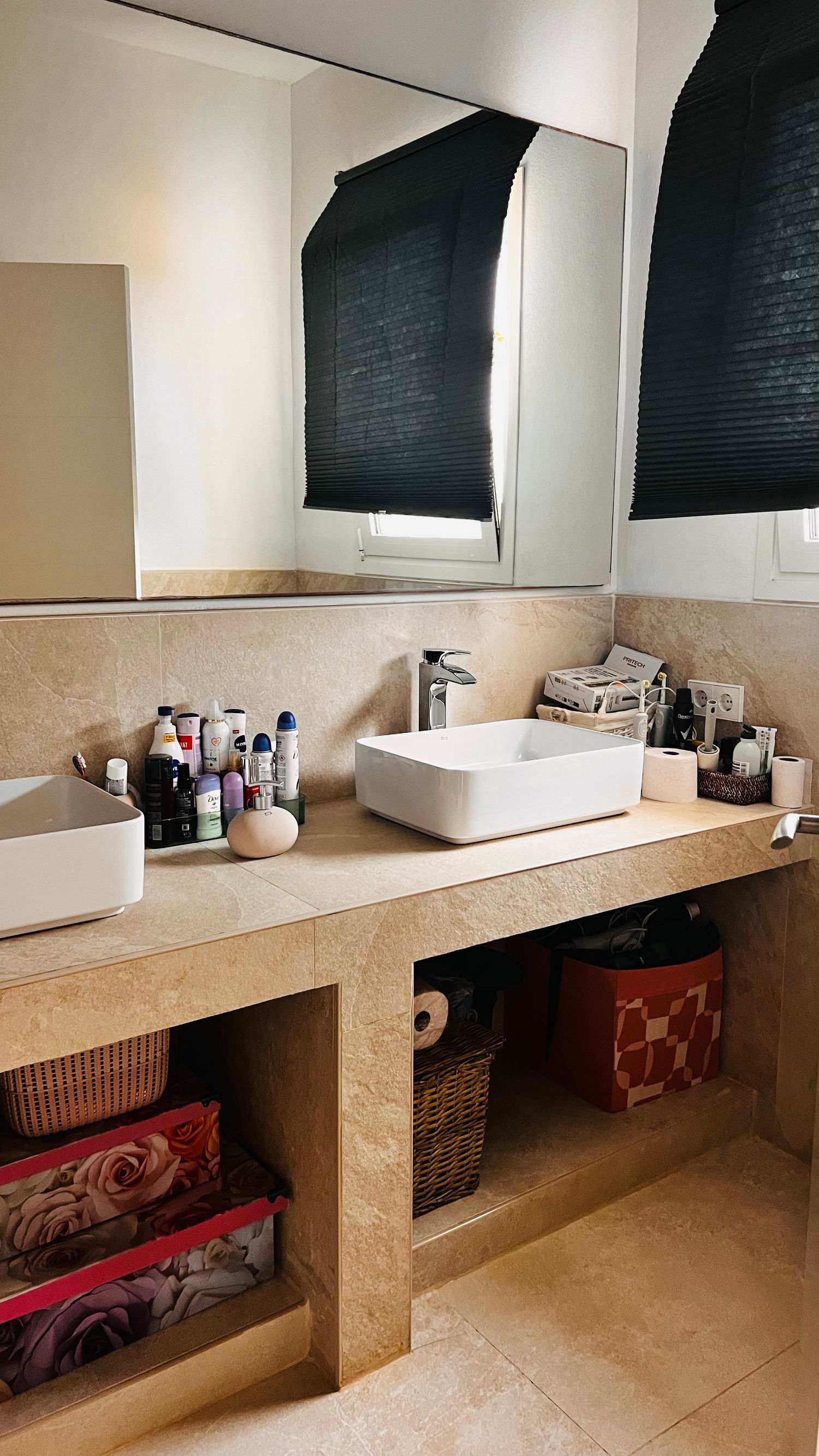 A modern bathroom vanity with a wooden countertop, a vessel sink, and various personal care items displayed on the shelves.