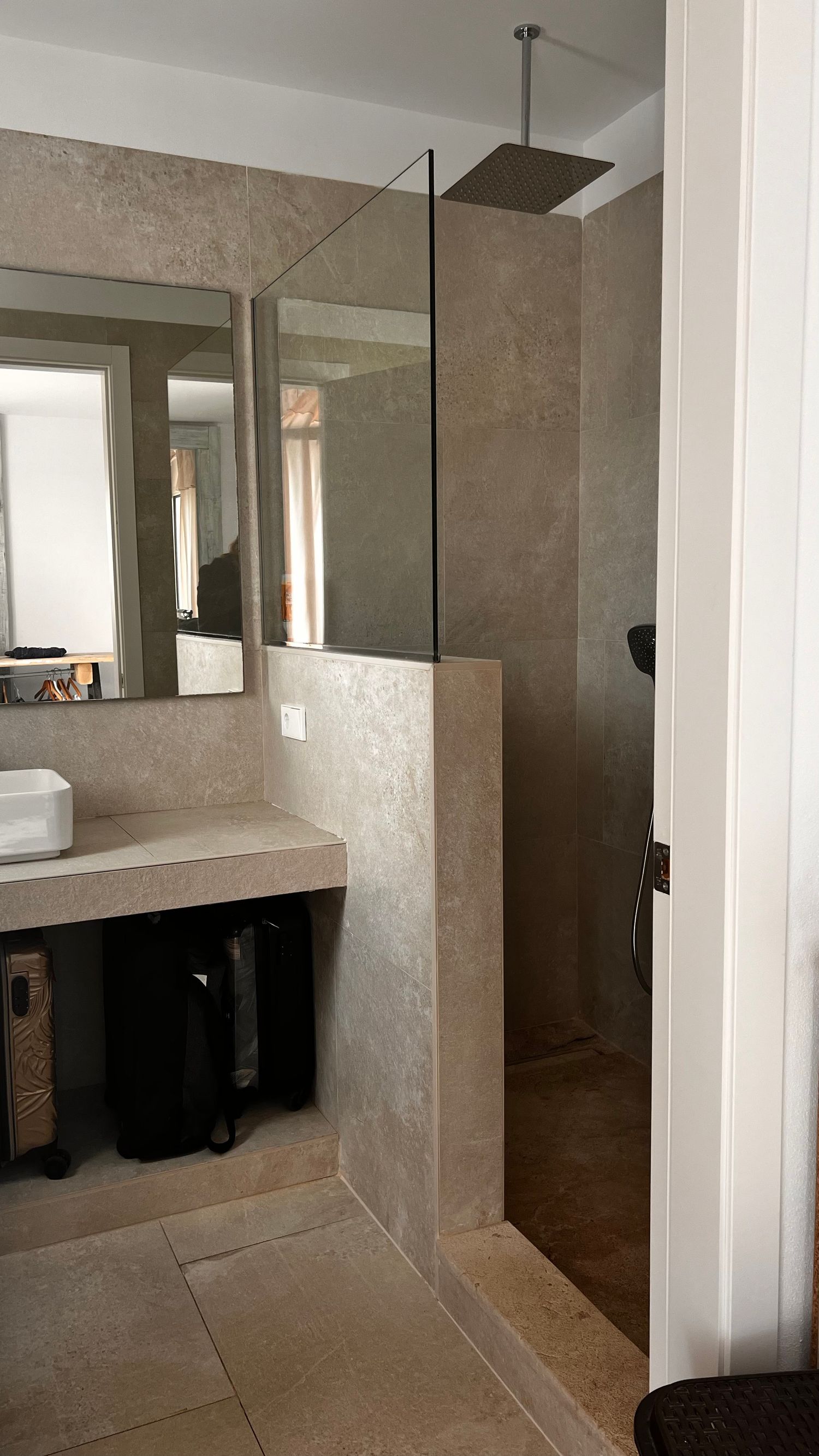 A modern bathroom with a vanity, mirror, and glass shower enclosure in a neutral color scheme.