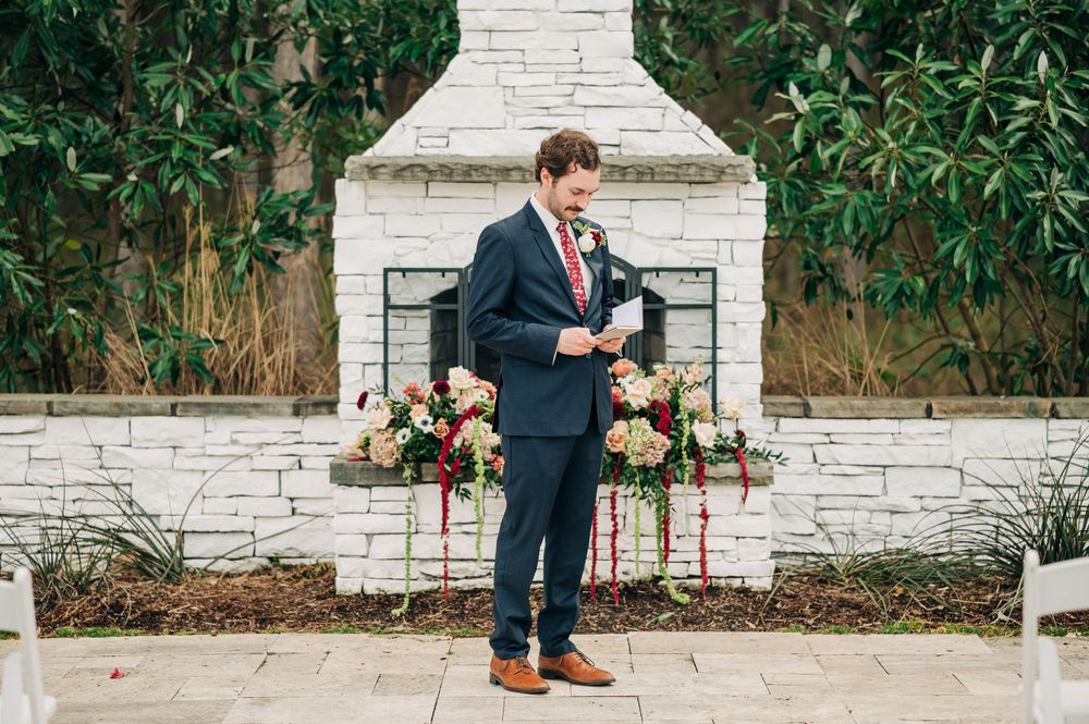 A wedding couple's feet and legs stand together outdoors with brown dress shoes and navy suits.