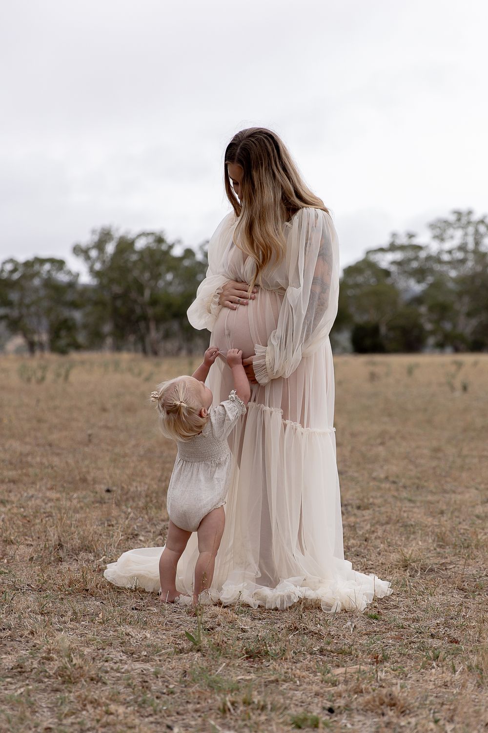 Mother to be and toddler in the paddock during a professional maternity photo shoot.
