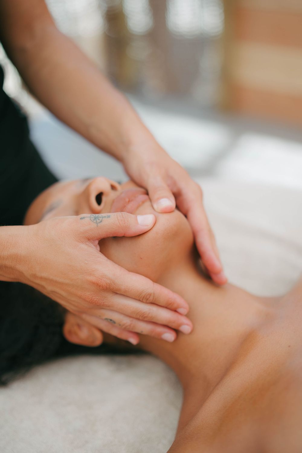 Un thérapeute effectue un massage facial relaxant sur un client allongé sur une table de traitement dans un spa.
