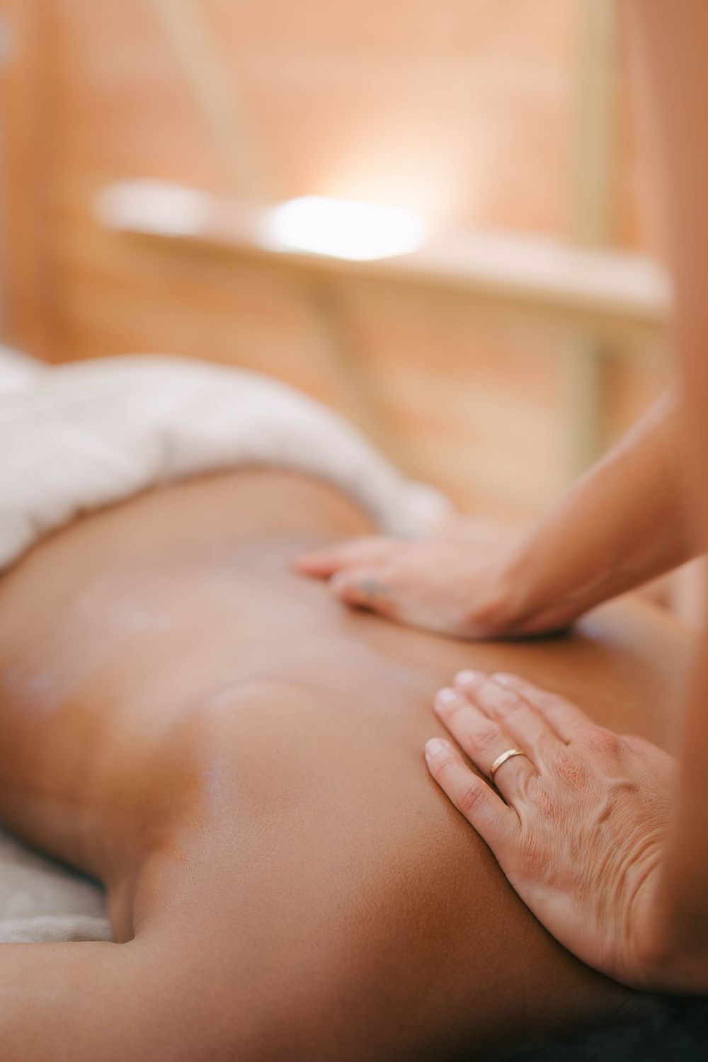 A massage therapist's hands performing a relaxing back massage on a client in a warm spa setting.