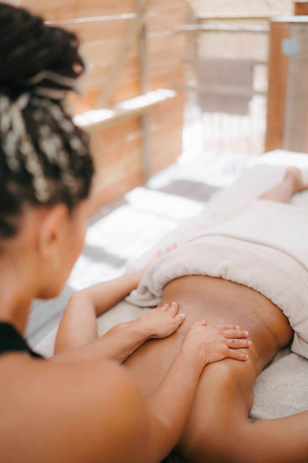 Un massothérapeute effectuant un massage relaxant du dos sur un client recouvert de serviettes blanches dans un spa.