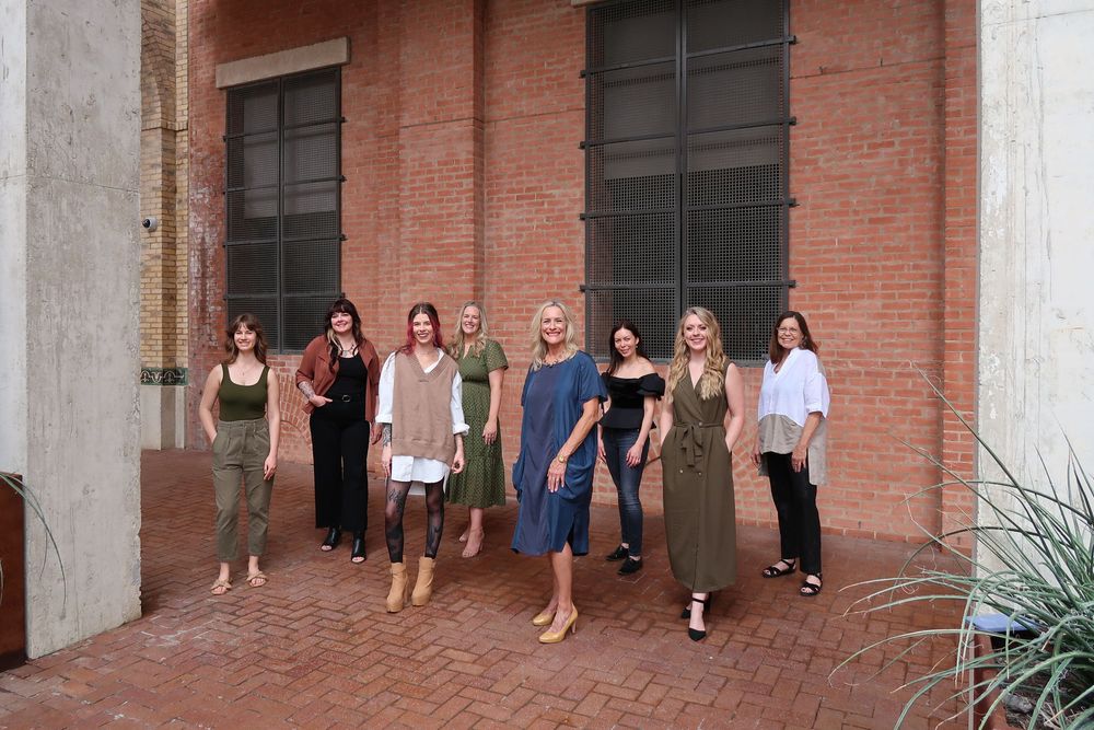 Group photo of people standing against brick wall exterior.