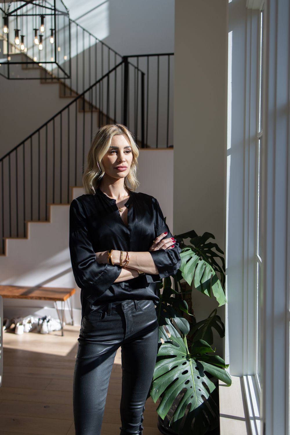 Modern interior with black silk blouse and monstera plant by window.