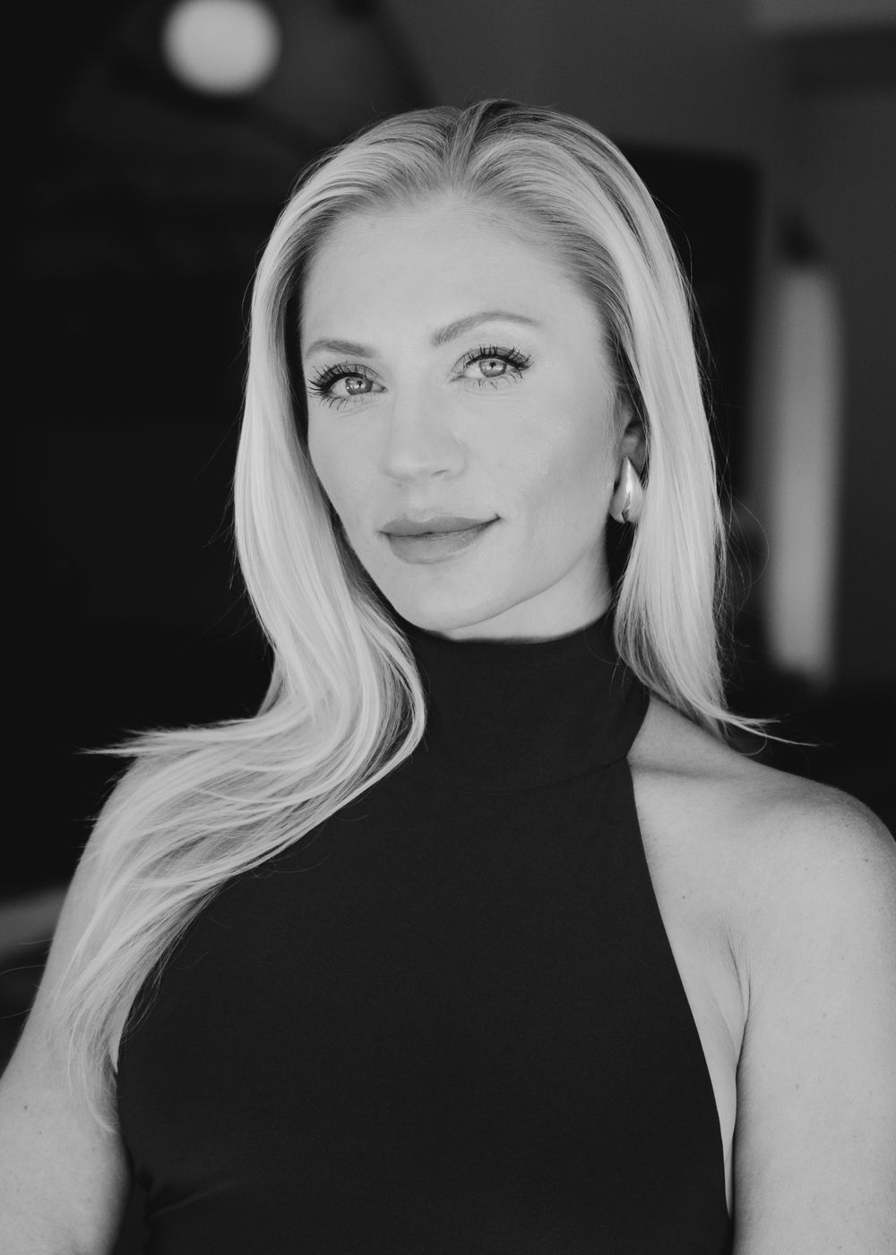 Black and white portrait of woman in sleeveless turtleneck with blonde hair.