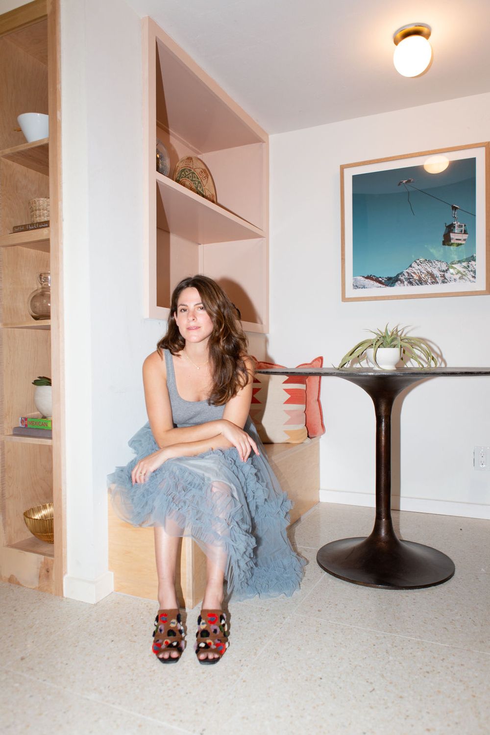 Person in blue dress lounges on white floor near modern furniture.