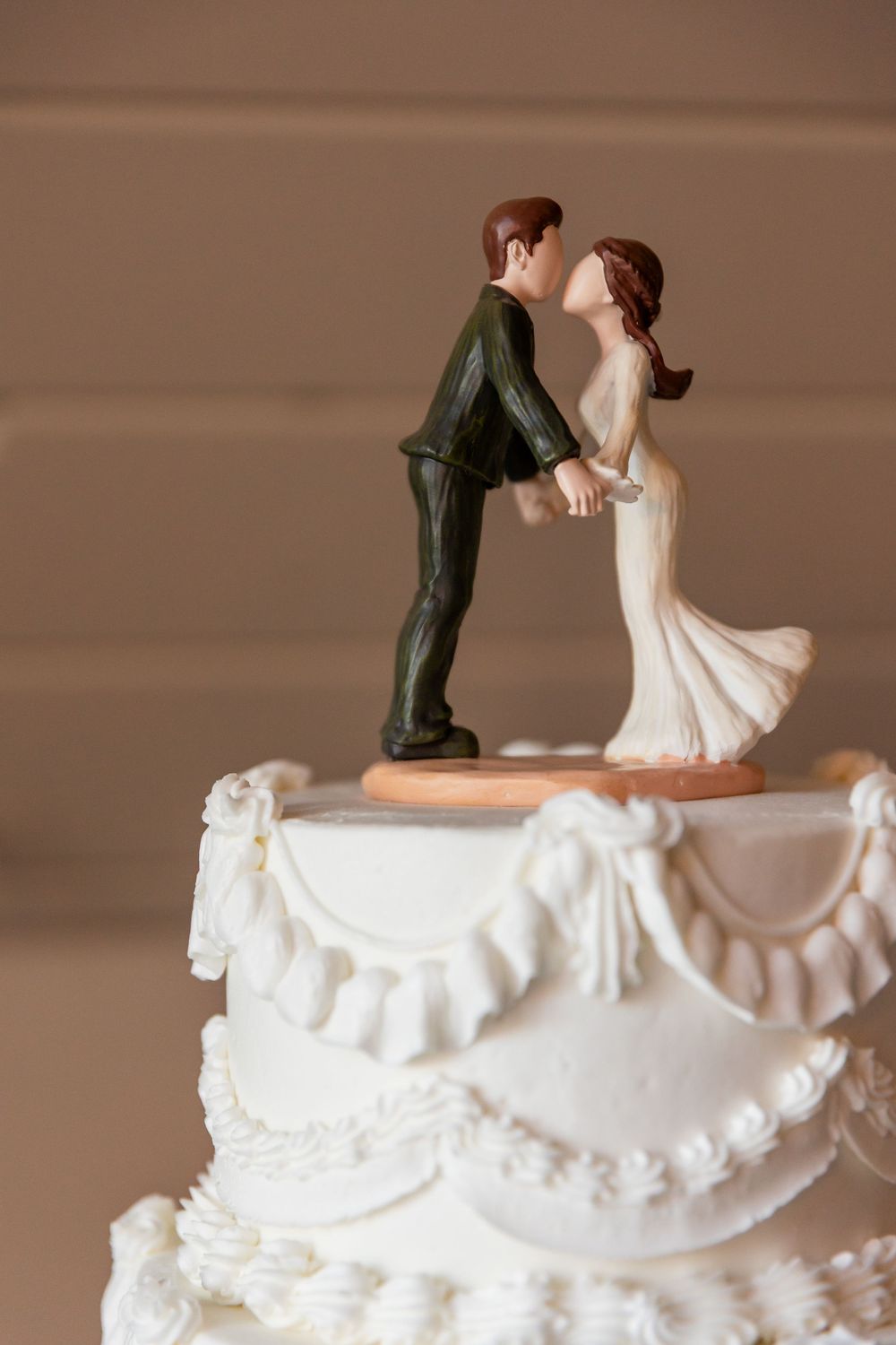 Classic white wedding cake topper featuring bride and groom figurines sharing a romantic kiss.