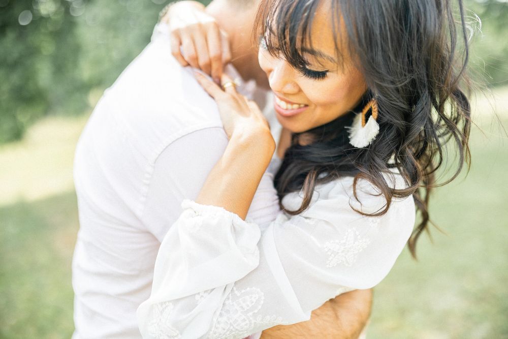 A candid outdoor portrait showing two people embracing in soft natural light.