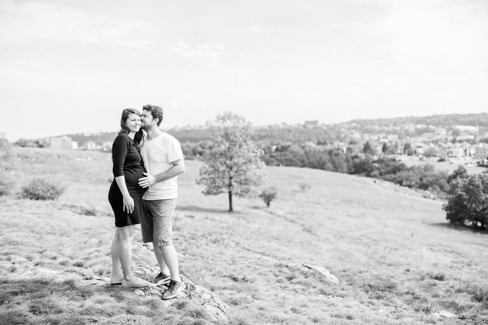A couple shares a tender moment on a hilltop overlooking a scenic landscape.
