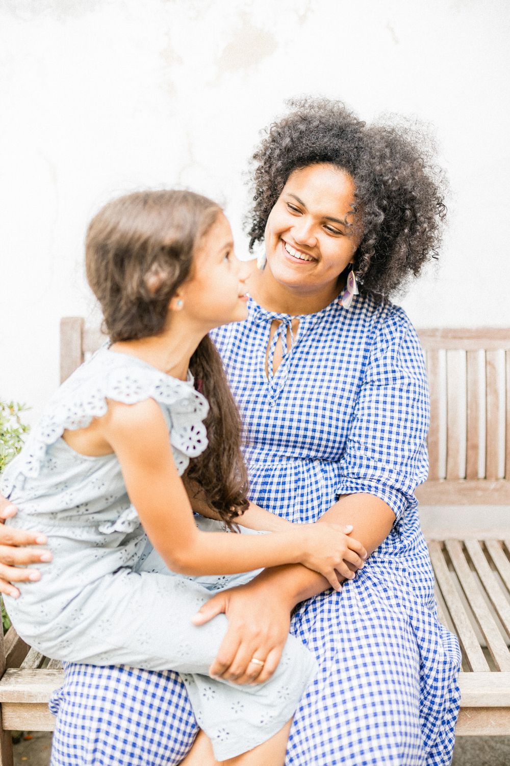 Two people sharing a joyful moment while sitting on a wooden bench outdoors.