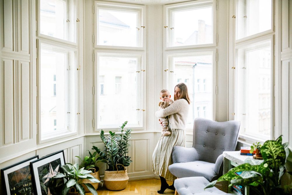 A tender moment shared in a bright room with windows and houseplants.