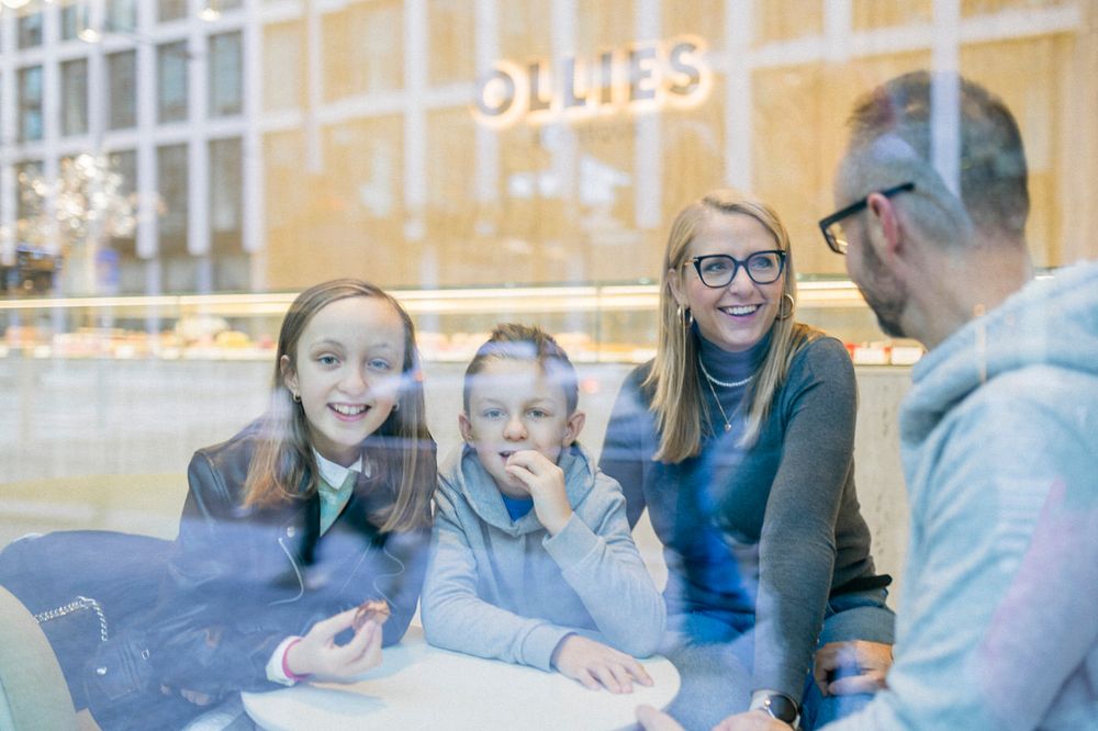 A group sharing a lighthearted conversation through a window reflection.
