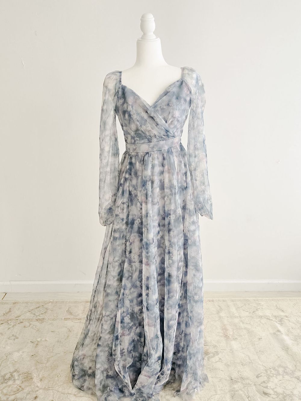 A flowy blue and gray floral print dress with long sleeves and empire waist displayed on a white mannequin.
