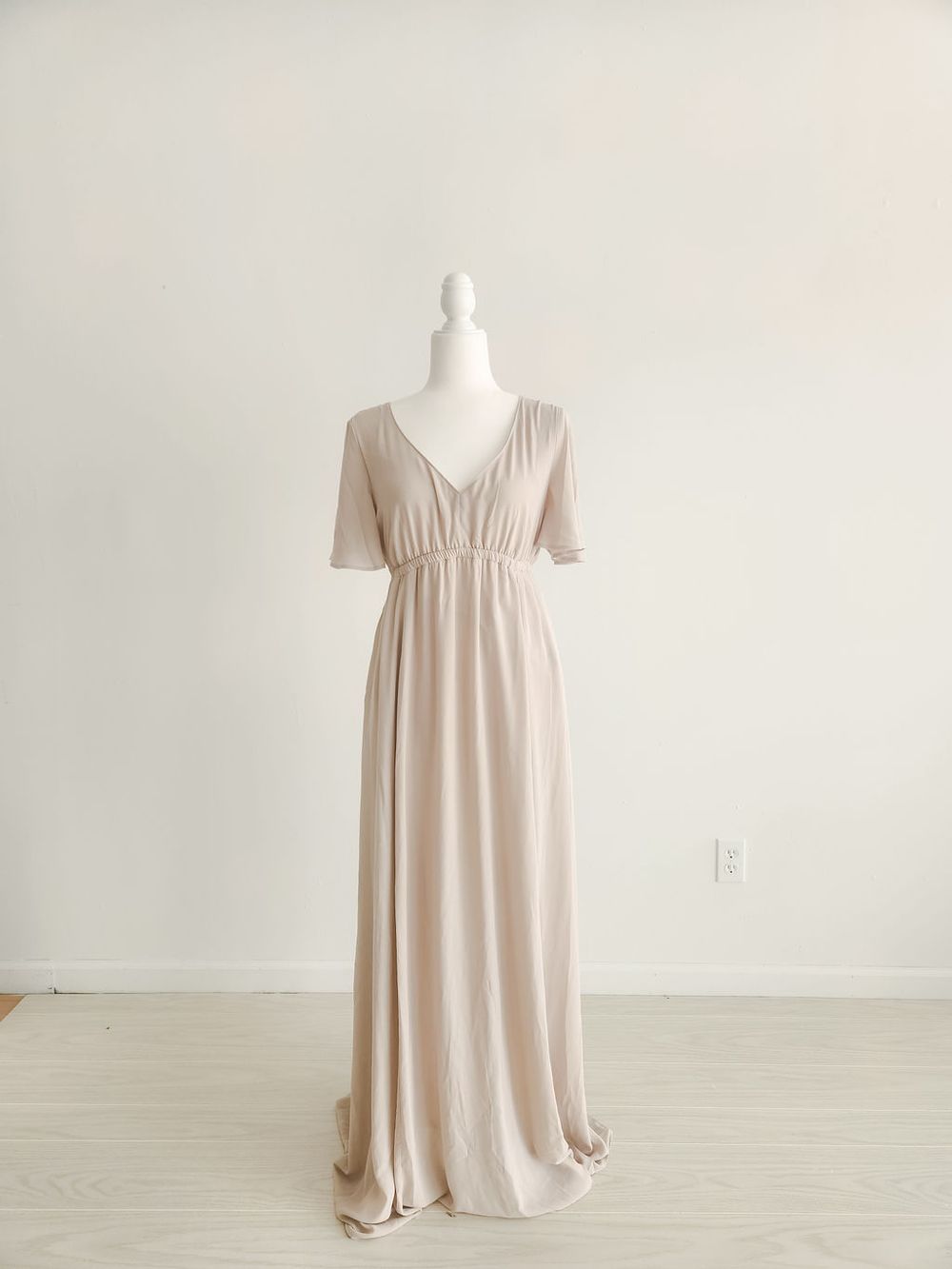 Blush pink babydoll dress with short sleeves displayed on white mannequin against light background.